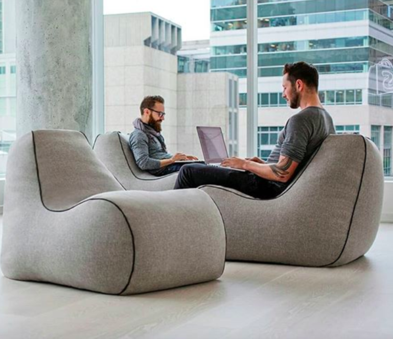 Three lounging bean bag chairs with two models sitting and working on their laptops 