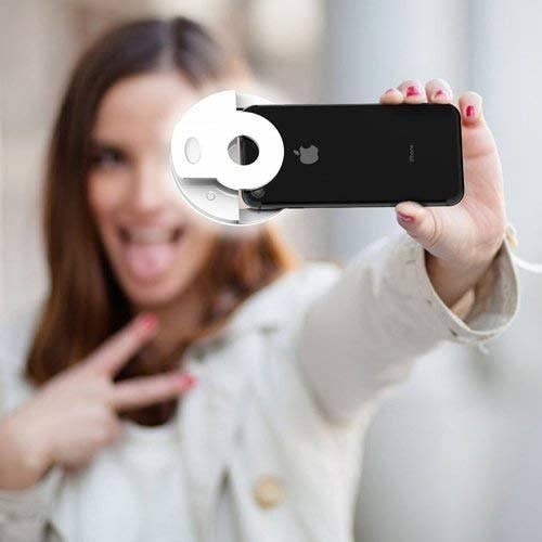 model uses round light on phone to take selfie 