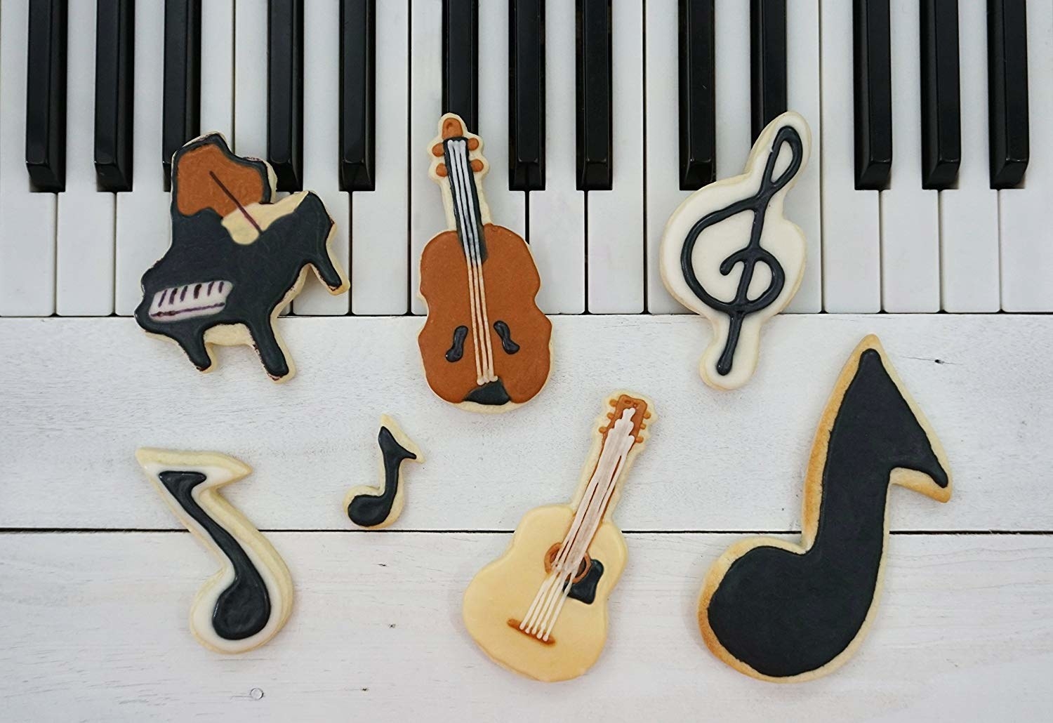 Seven cookies in the shape of music notes, guitars, and a piano