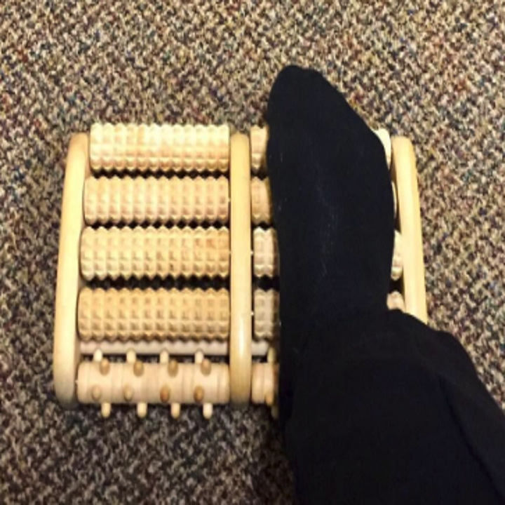 a reviewer's foot on the wooden massager