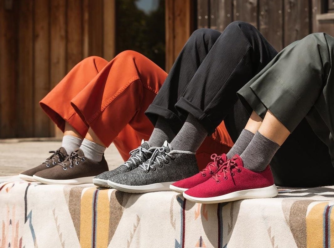 Models wearing the sneakers in brown, gray, and red