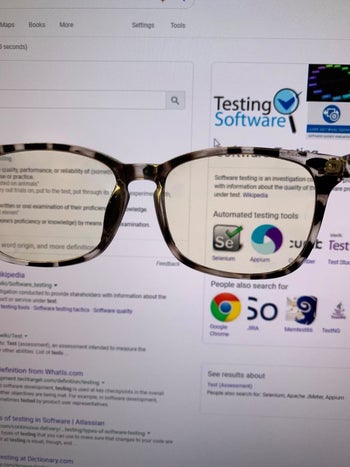 A reviewer holding the glasses up to a computer screen. The screen appears yellow through the lens of the glasses