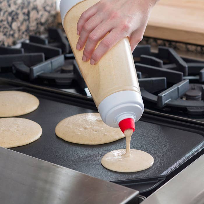 A person pouring pancake batter onto a griddle