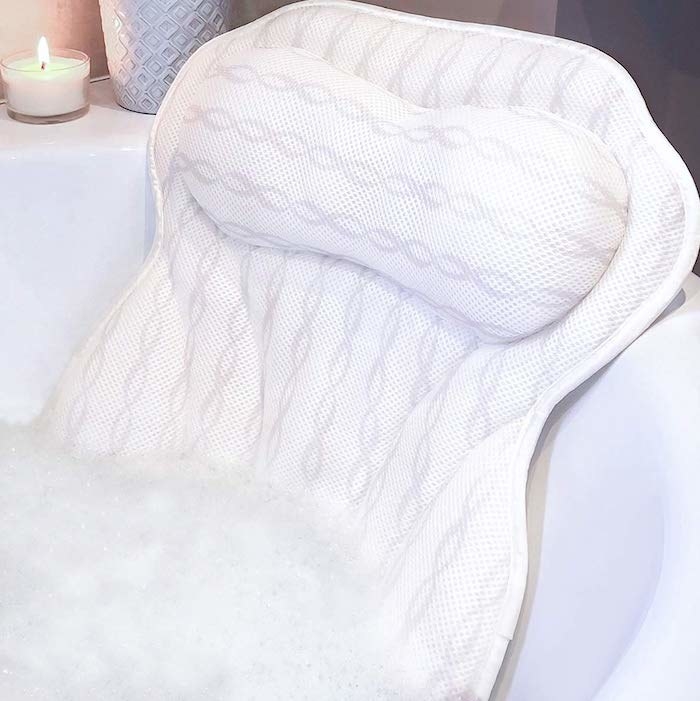 The bath pillow placed over the edge of a tub full of bubbles