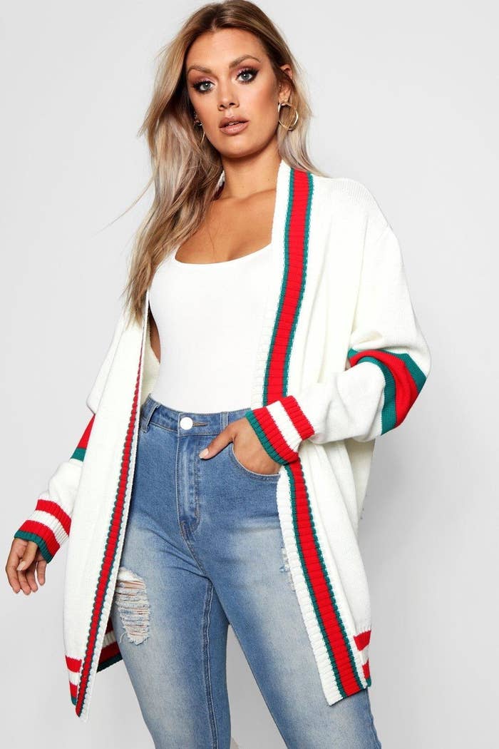 a model in a white open cardigan with red and green stripes as accents