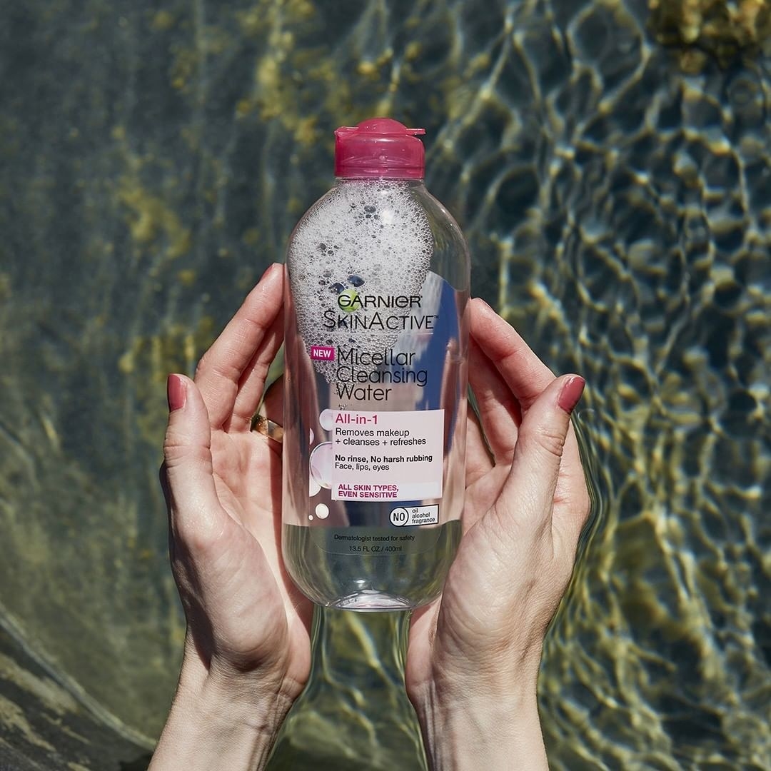 A pair of hands holding the bottle of micellar water