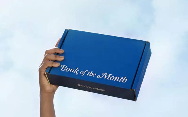 hand holds cardboard box that says book of the month 