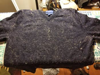 Before photo of reviewer's dark gray sweater, which is covered in white lint and pilling