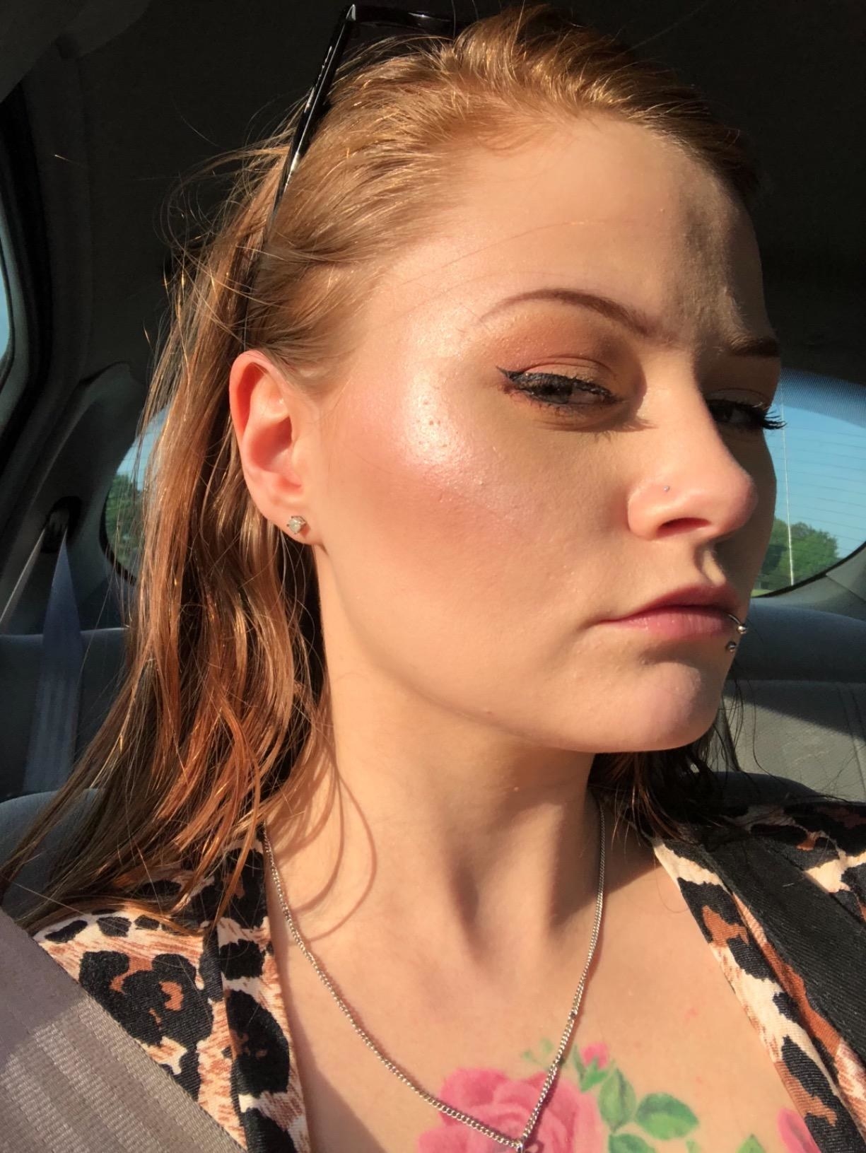 A reviewer showing the side of their face, which looks radiant and shimmery with the product on