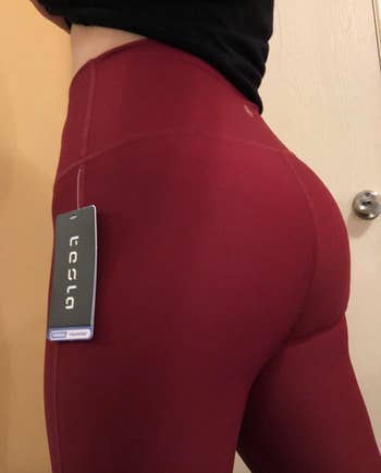 reviewer wearing the leggings in maroon, with closeup shot of their bum to show that they are not see-through 
