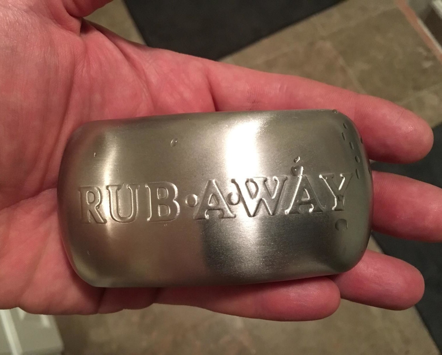reviewer holding stainless steel soap bar reading &quot;rub-a-way&quot;