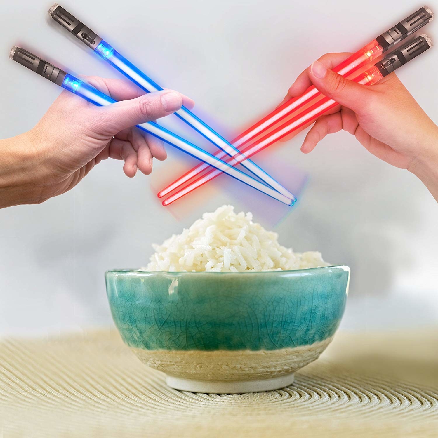 two hands holding up two pairs of light saber chopsticks