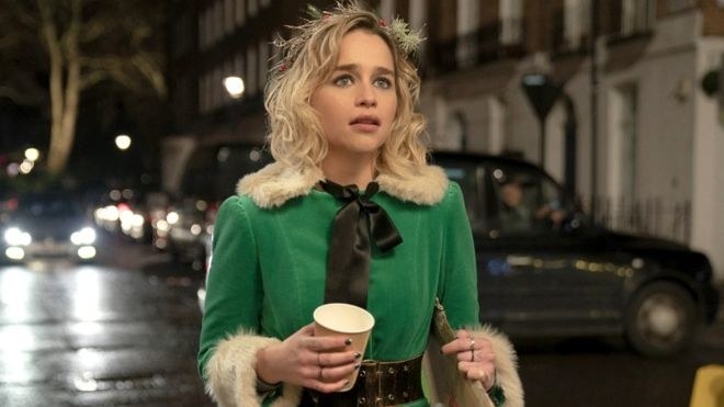 emilia clarke as kate in last christmas walking down a street at night