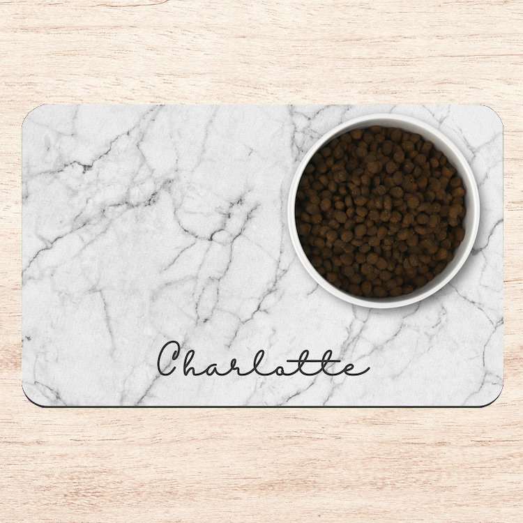 a placemat designed to look like white marble with a dog&#x27;s name written on it in script font