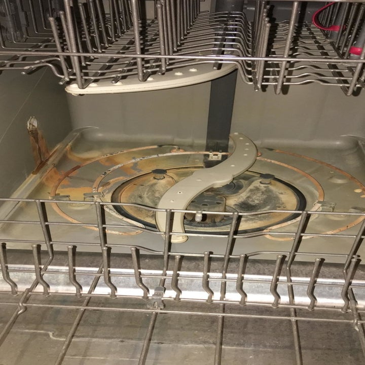 A dirty dishwasher with brown stains on the bottom