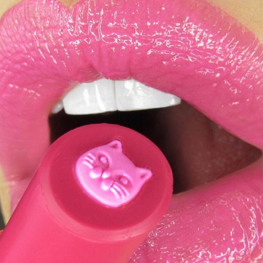 The pink lipstick with a cat in the middle being applied on lips