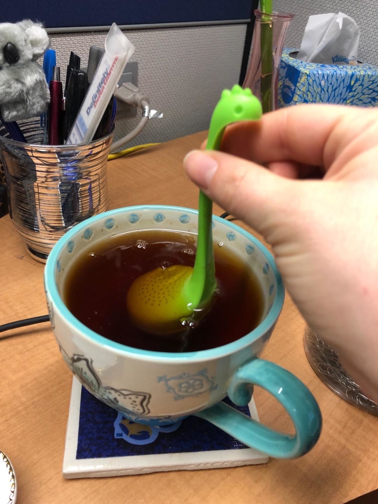 The green infuser in a cup of tea
