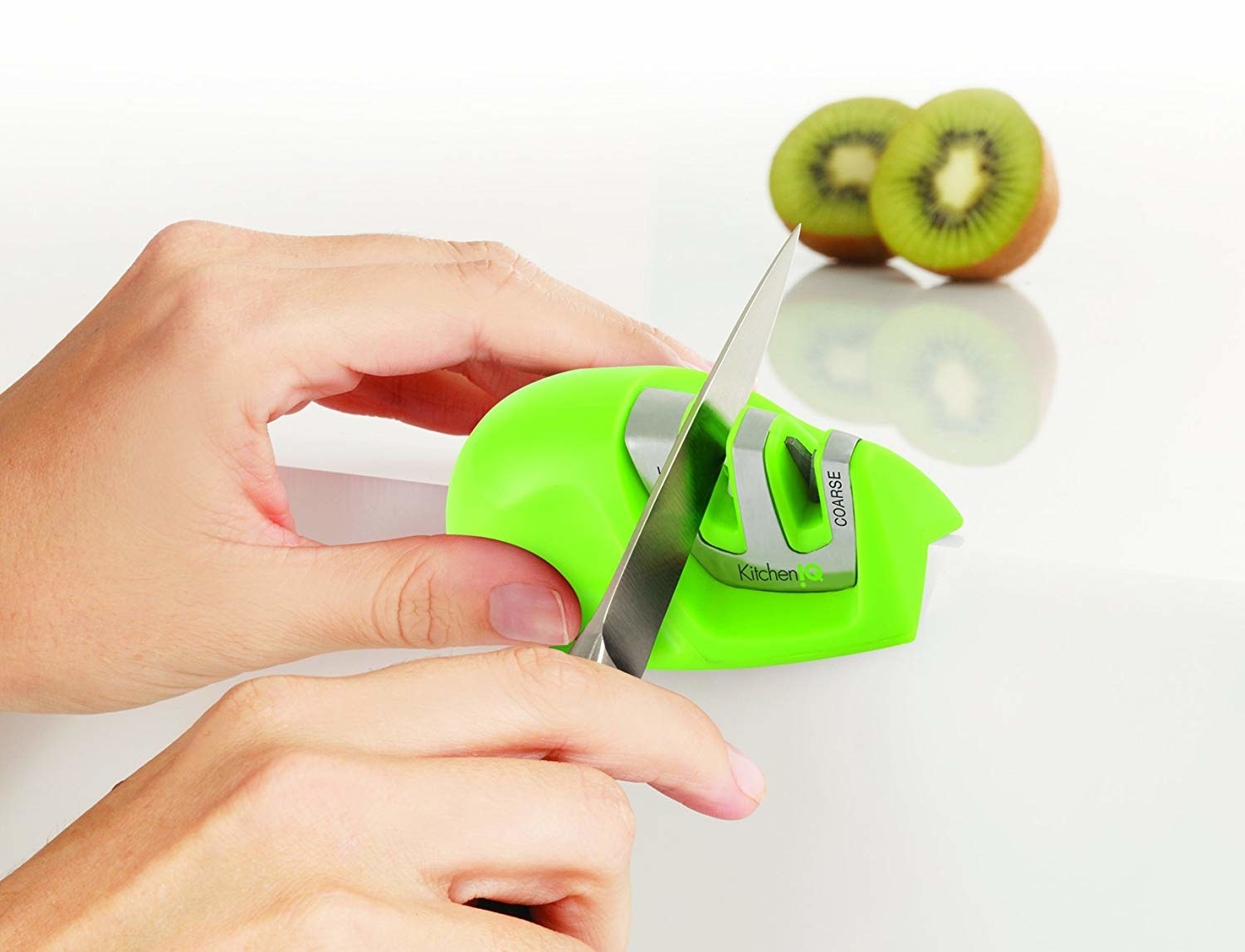 Hand gliding knife through a slit in a green knife sharpener