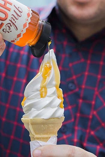 Hand drizzling Mike's Hot Honey on an ice cream cone