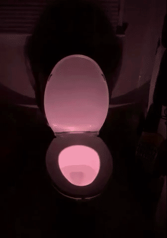 a toilet with the light in it, alternating different colors in the dark