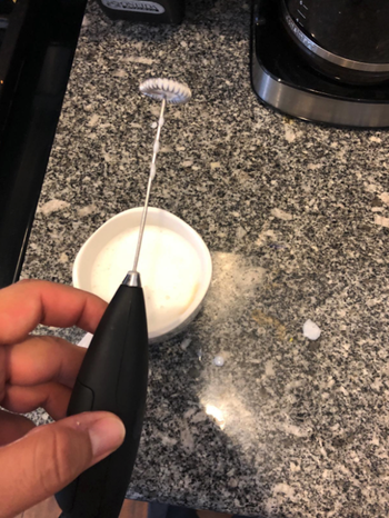 Reviewer's hand holding the frother