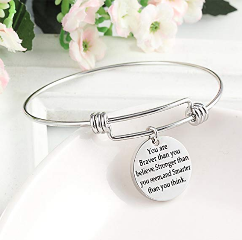 A metal bracelet with a charm on a board