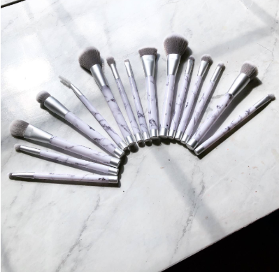 set of makeup brushes with marble-print handles fanned out on tabletop