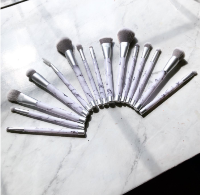 set of makeup brushes with marble-print handles fanned out on tabletop