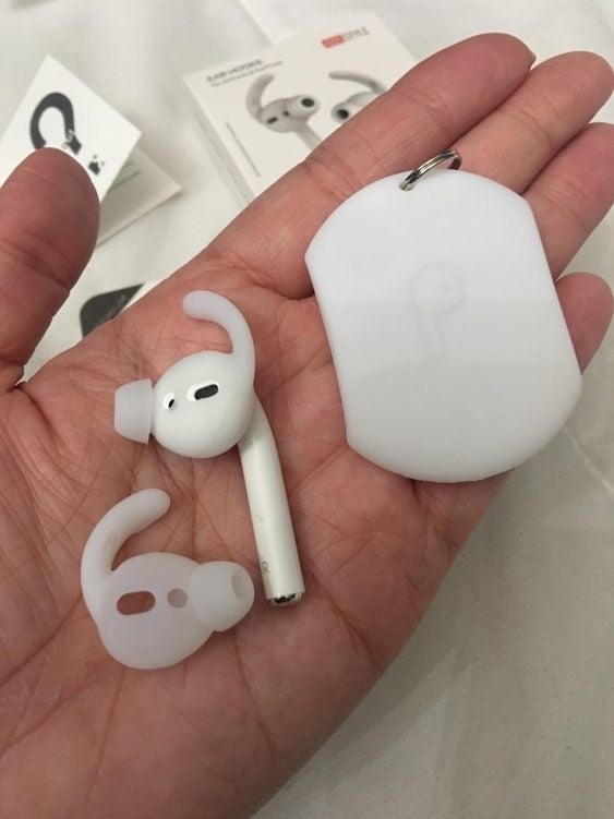 Reviewer holding the silicone ear hooks attached to their AirPods