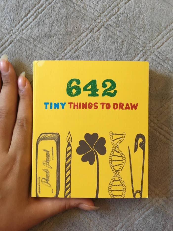 small book that says 642 tiny things to draw being held between forefinger and thumb to show small size 