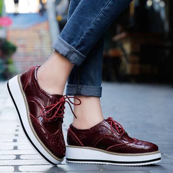 A model wearing the burgundy patent oxfords with chunky white and black platform soles