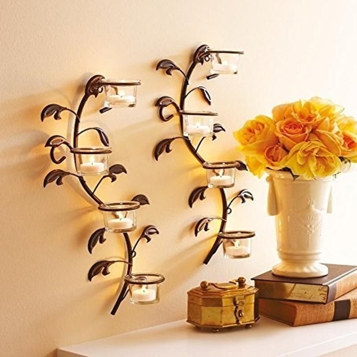 A vine-shaped candle holder with candles on it next to a vase