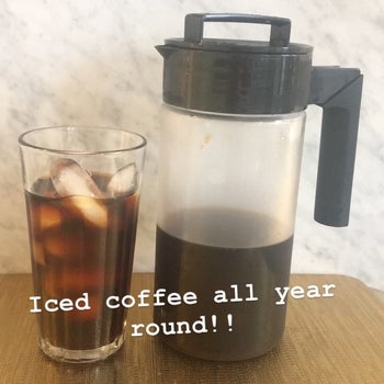 iced coffee in clear glass next to the cold brew maker labeled 
