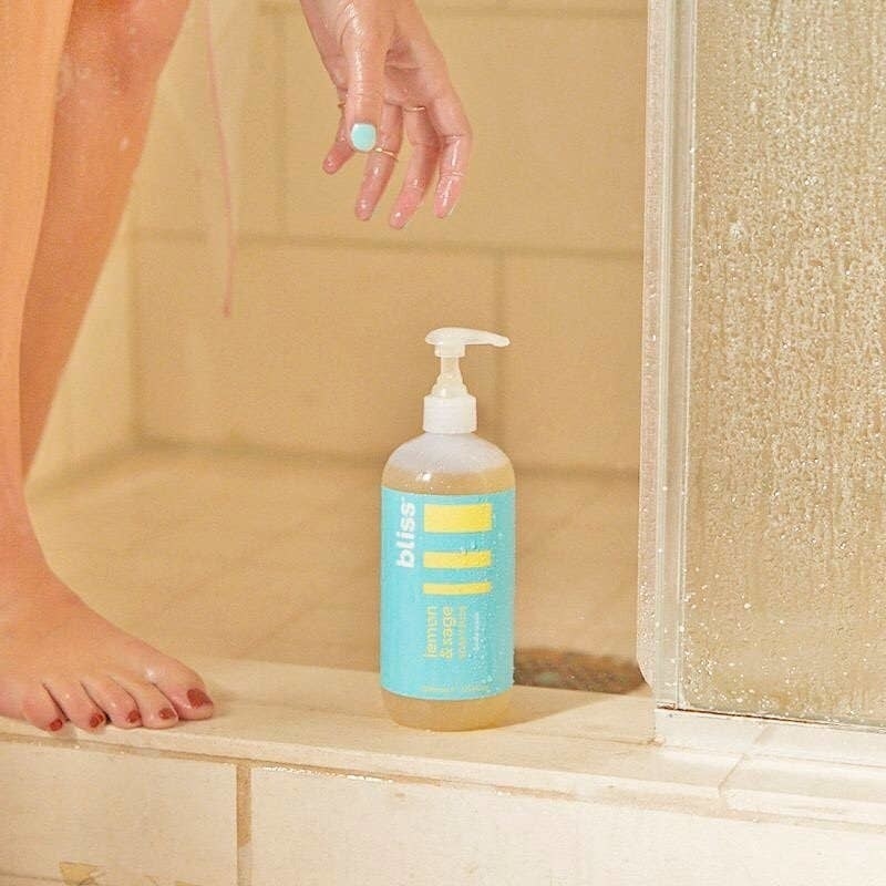 model reaching for the body wash in the shower