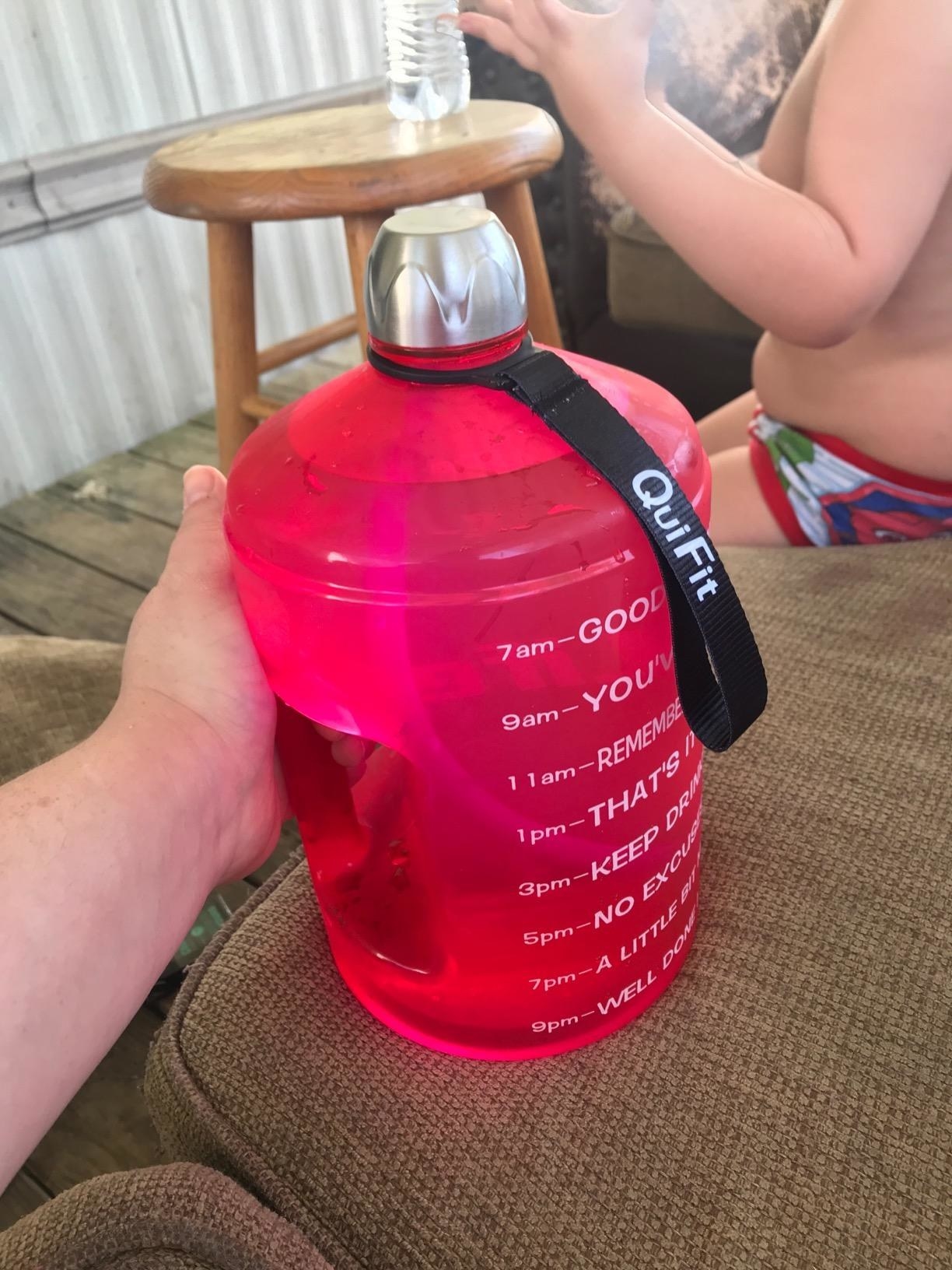 A reviewer showing the large water bottle time stamped with motivational phrases in pink