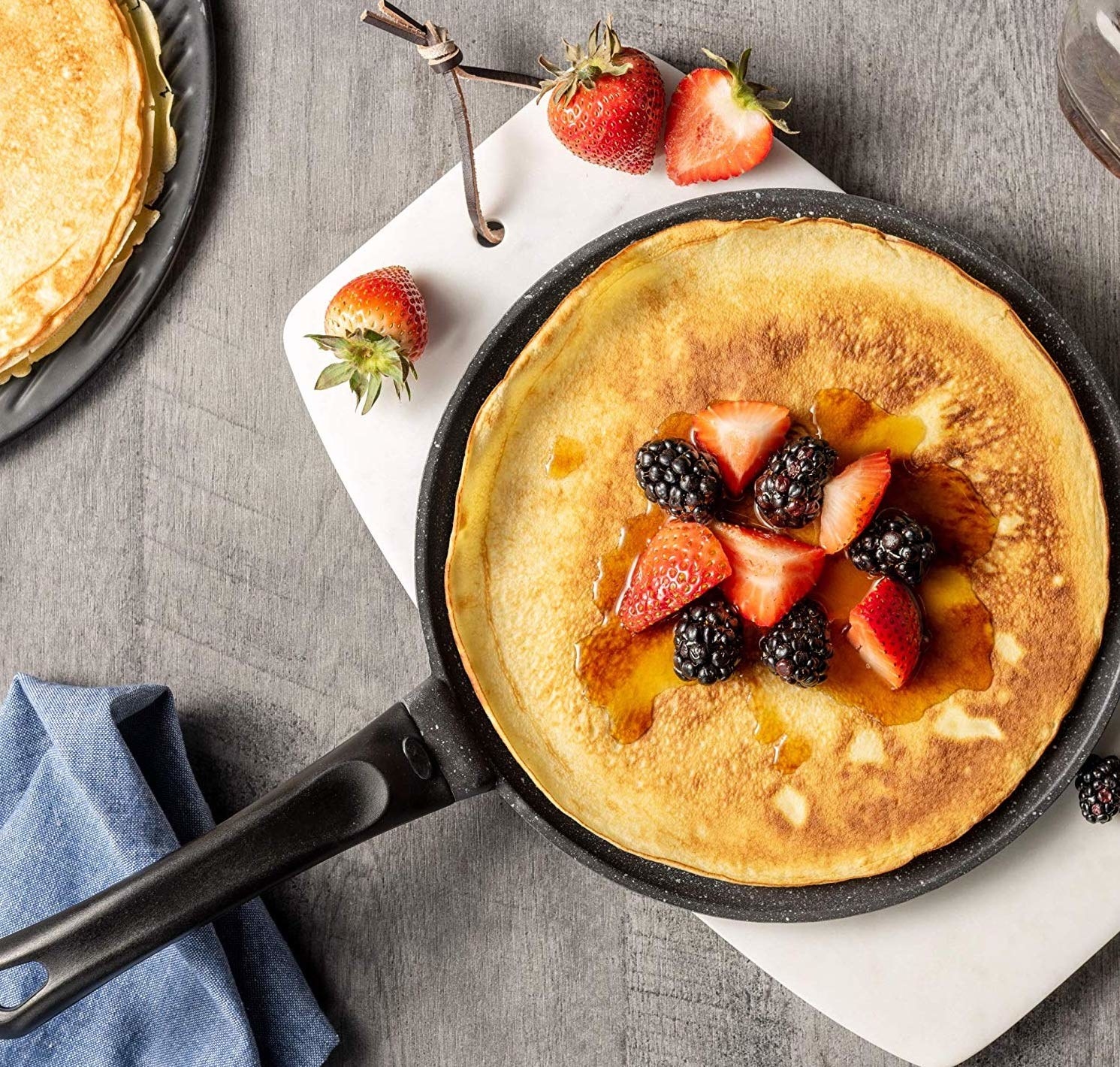 A crepe on the pan topped with fruit and syrup