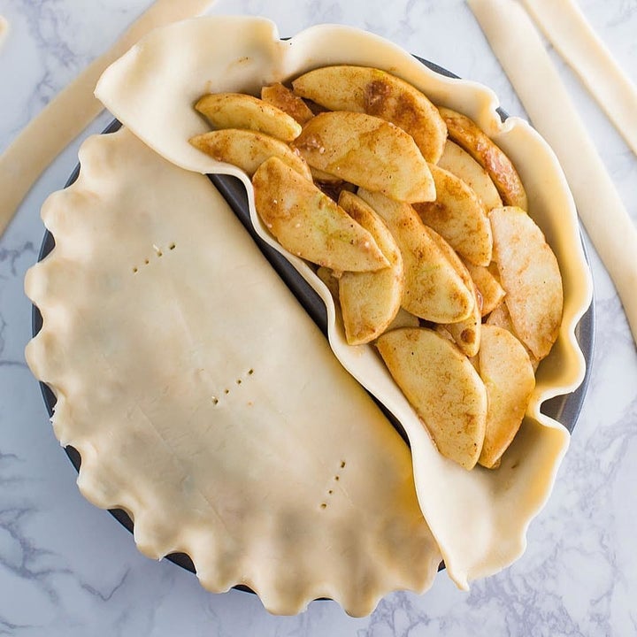 Two pies in the pan, one has its centre revealed and is filled with apples
