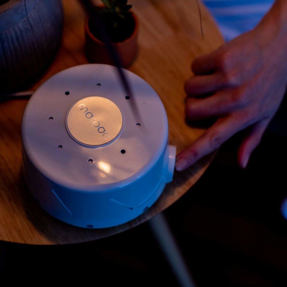 Round sound machine on bedside table 