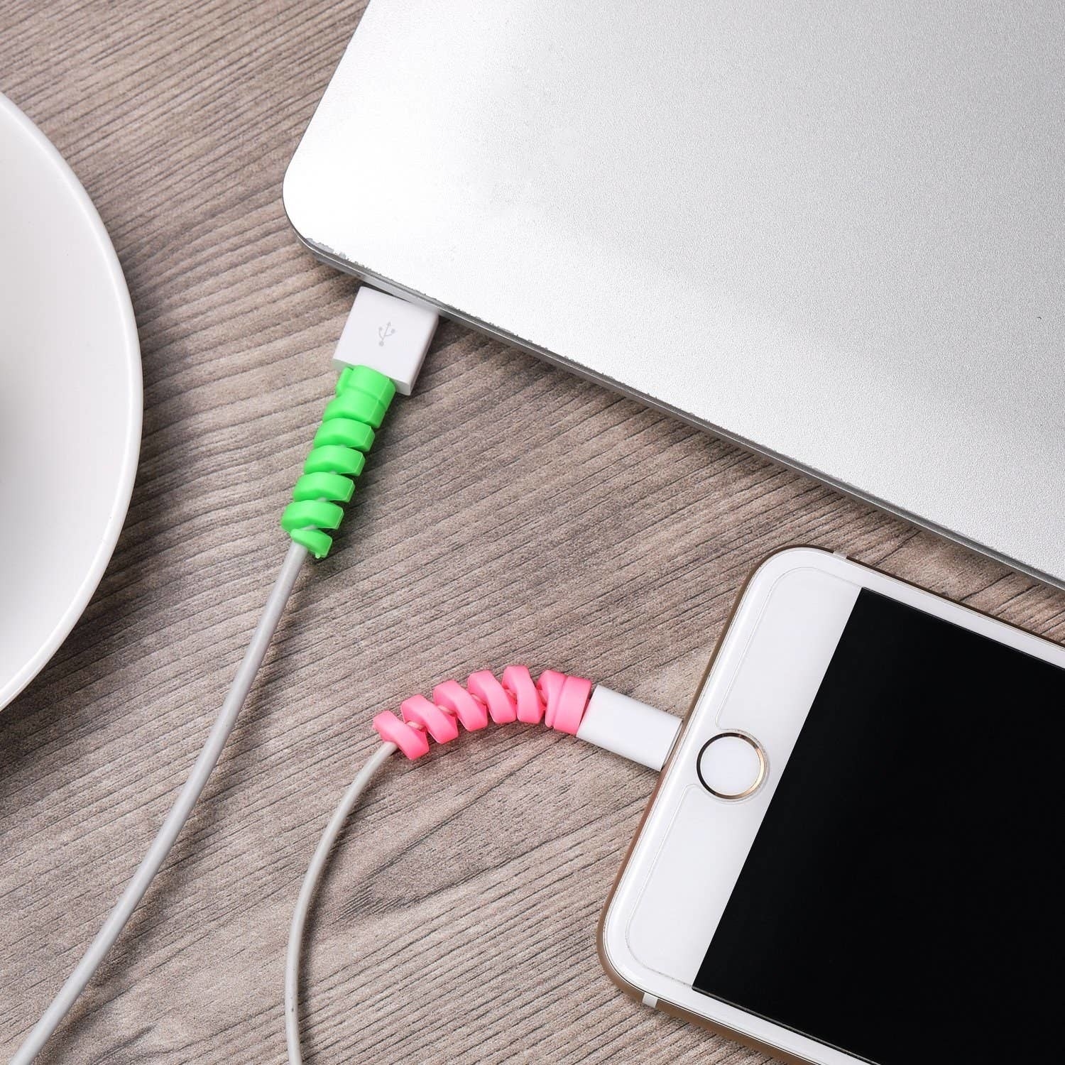 pink and green cord protectors on chargers for a laptop and iphone