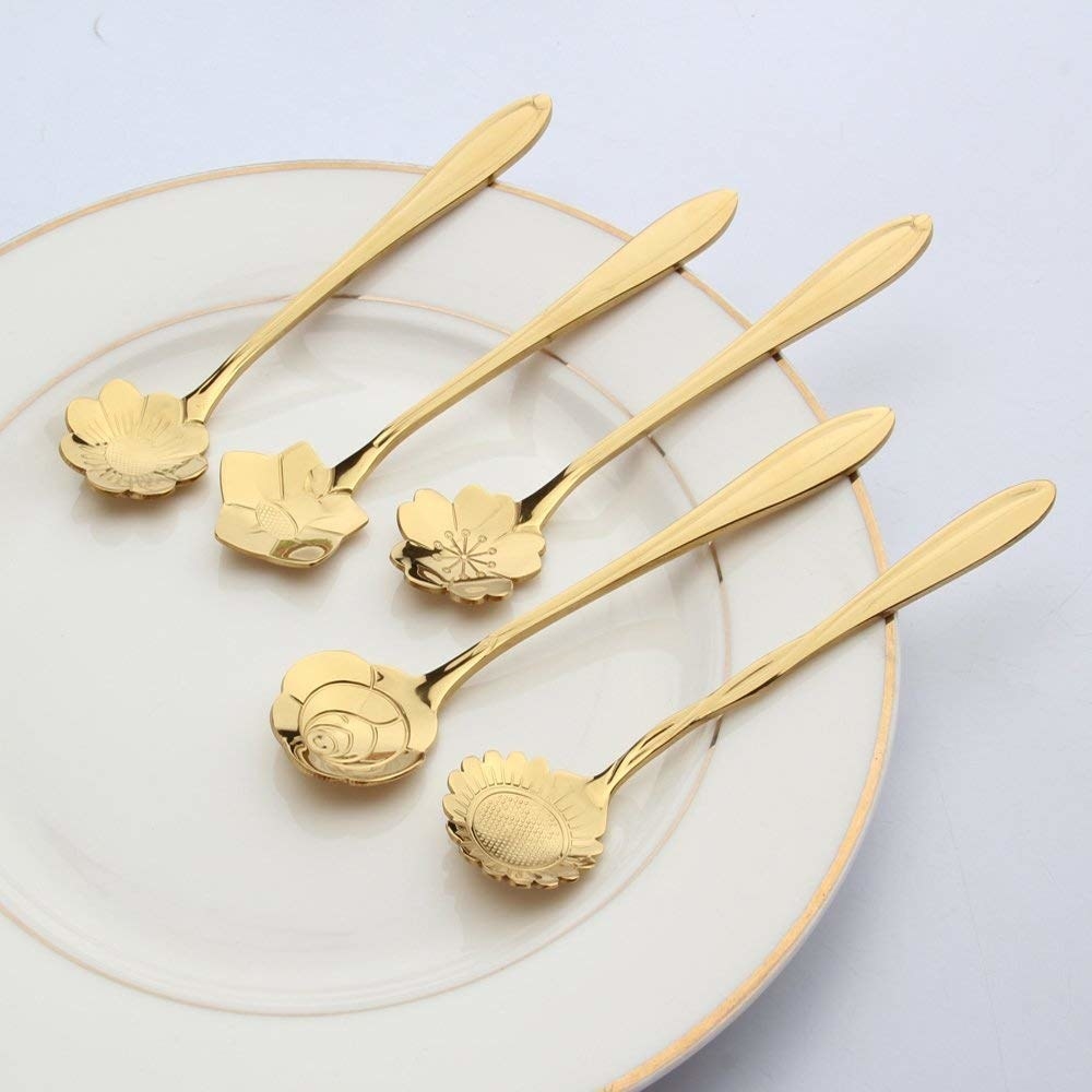 Five floral teaspoons on a plate