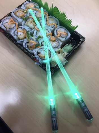 reviewer image of lightsaber chopsticks turned on near a plate of sushi