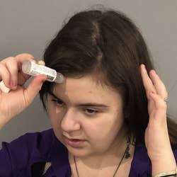 This a close-up of BuzzFeed editor Katy Herman applying the essential oil stick to her forehead.