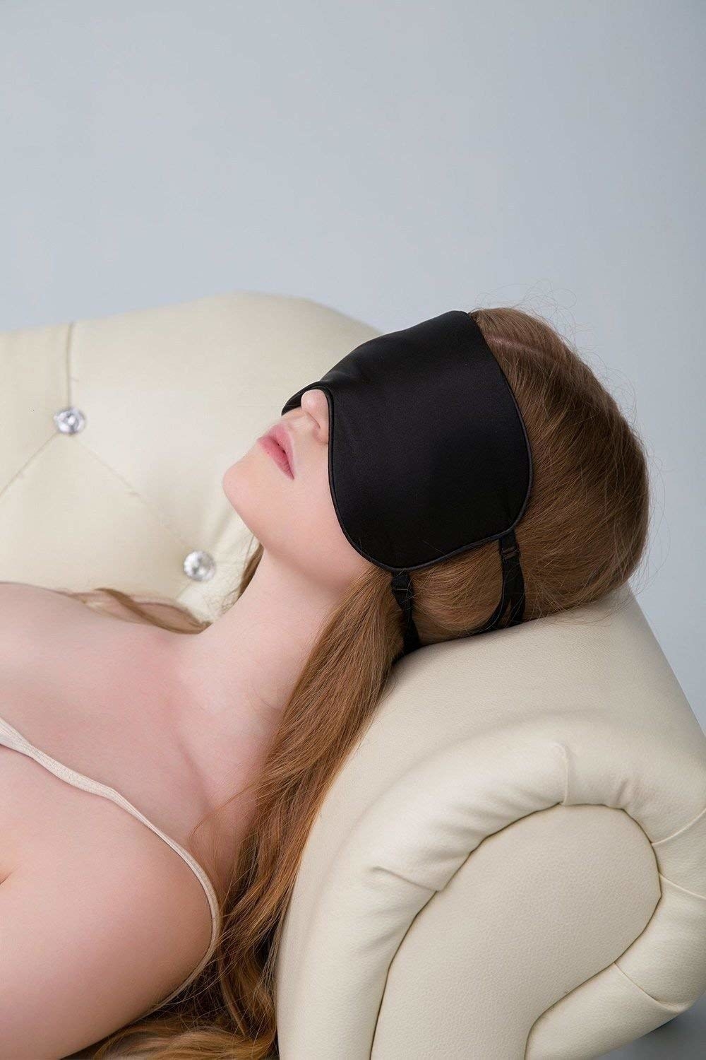model laying on a couch with the sleep mask on