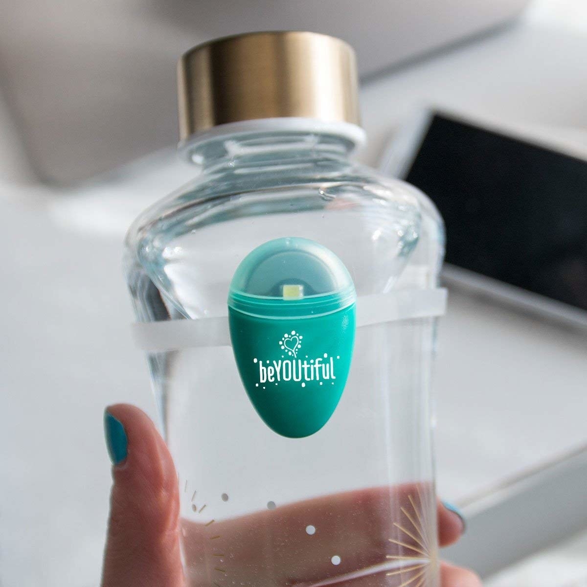 the device which has a light and the word &quot;beautiful&quot; written on it. it&#x27;s held to the bottle by a silicone ring (similar to a rubber band).