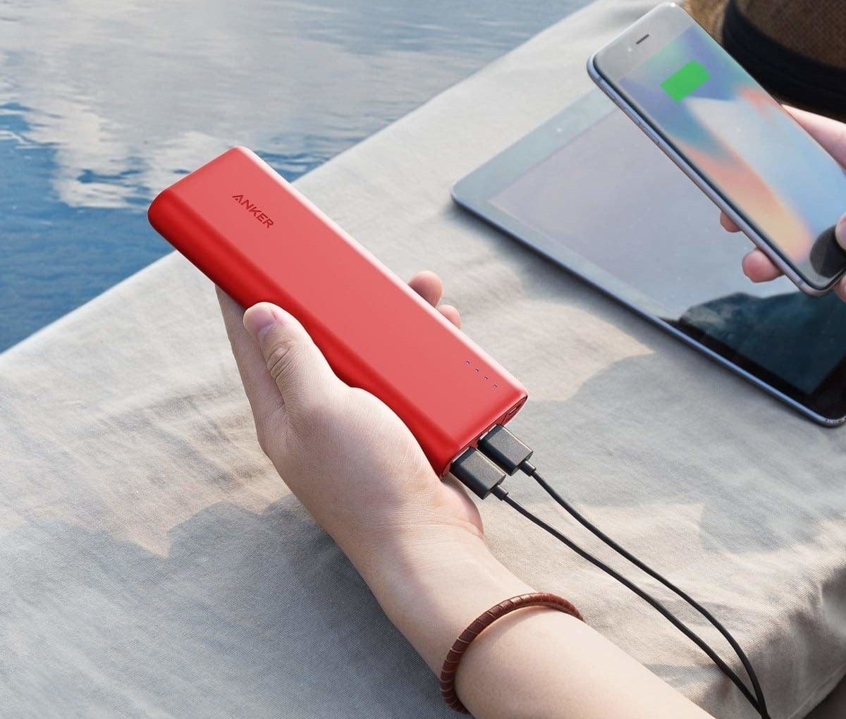 A person holding a slim rectangular power bank charger in their hand