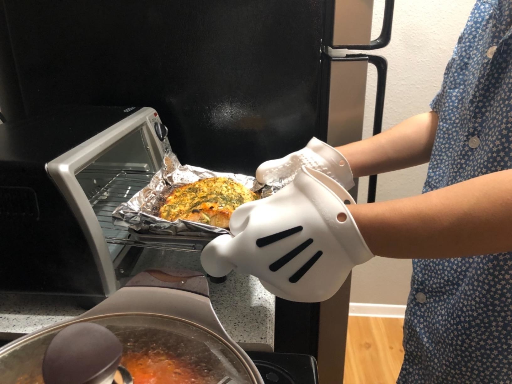 reviewer pulls meal out of oven wearing oversized mickey mouse gloves 