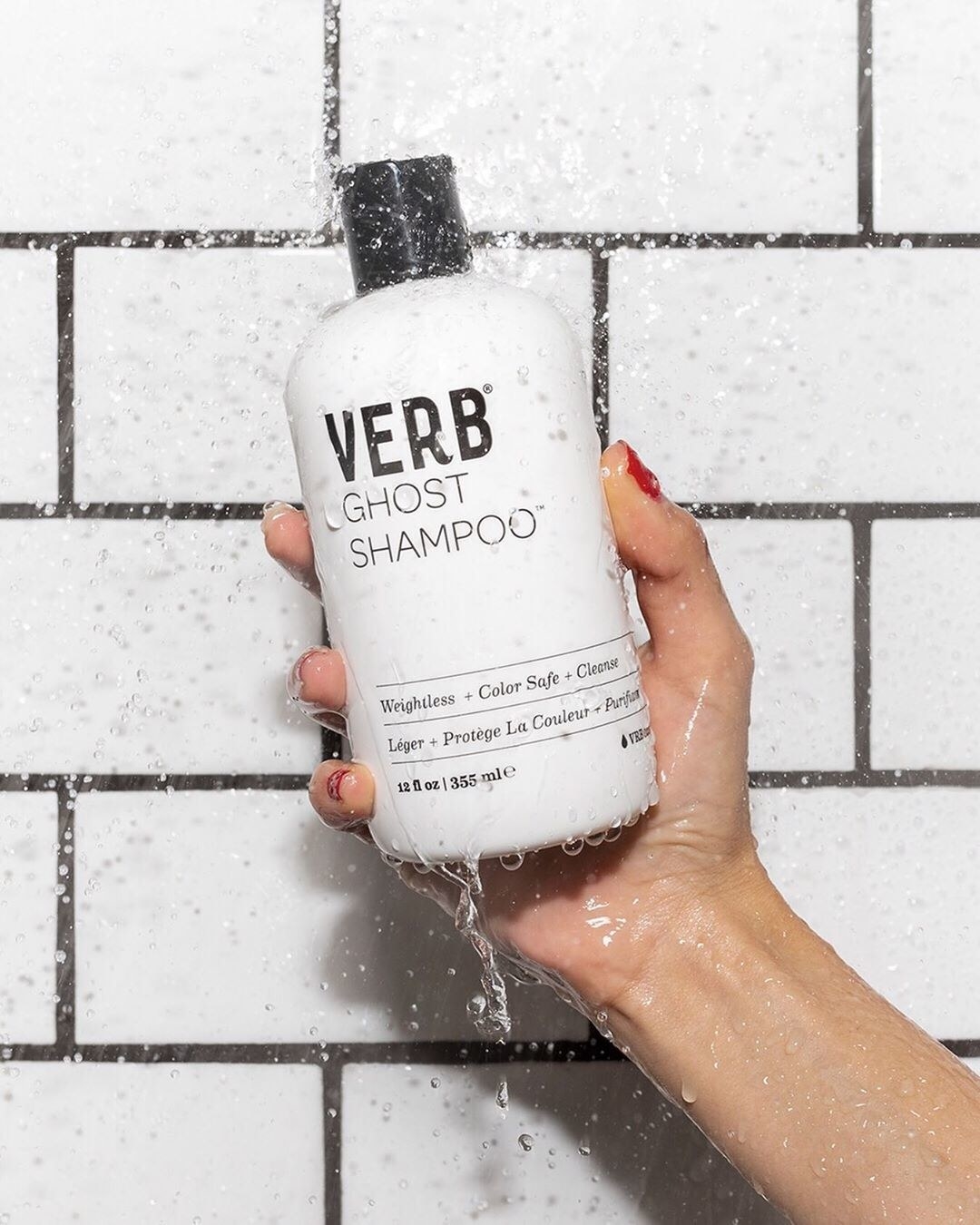 hand holding white bottle with black cap labeled &quot;verb ghost shampoo&quot; 