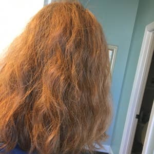 A reviewer's wavy, frizzy hair before using the hot air brush 