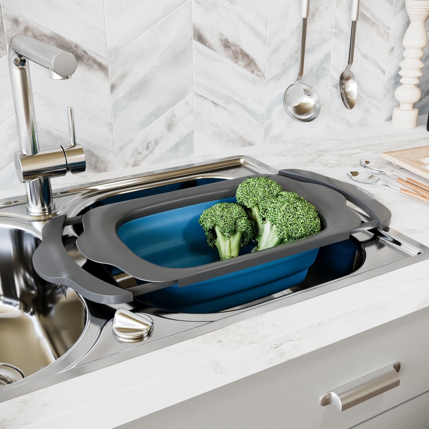 A large silicone colander resting on the edge of a the sink and filled with broccoli