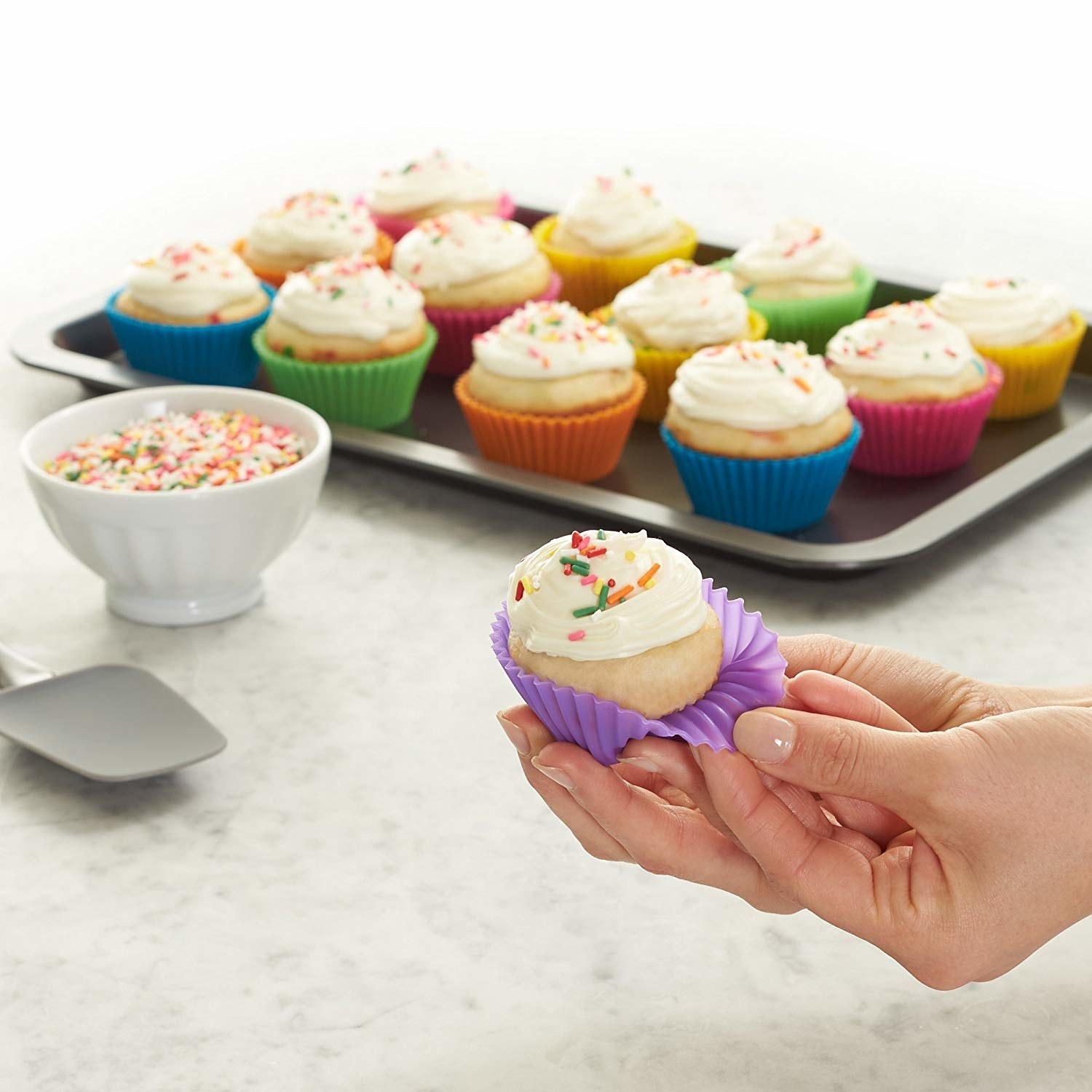 model pulls silicone cupcake holder off cupcake to show no crumbs are stuck to it 